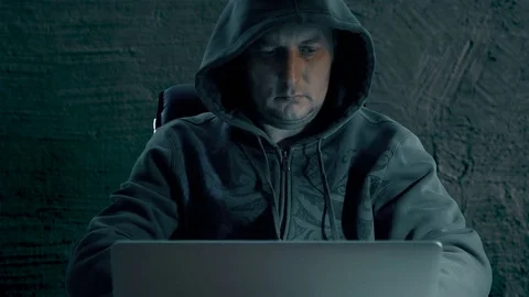 Hacker in a hoody sweatshirt is sitting at table at night and coding. Hacker man Stock-Footage 82632607
