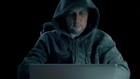 Hacker in a hoody sweatshirt is sitting at table at night and coding. Hacker man Stock Footage 82669771