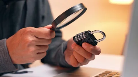 A hacker inspects a combination lock with a magnifying glass. Stock Footage 316567862