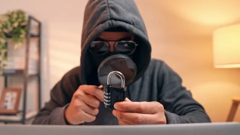 A hacker inspects a combination lock with a magnifying glass. Stock Footage 316567873