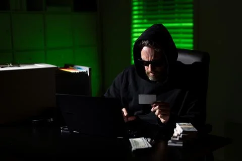 Hacker with laptop in a dark office. Anonymous hacker in a hoodie hacking data 스톡 사진