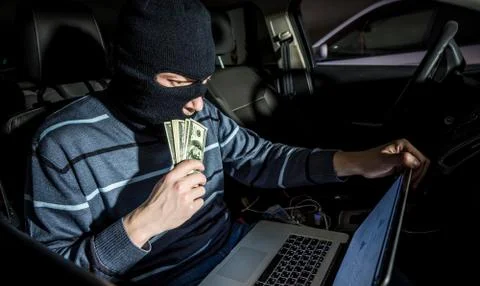 Hacker with a laptop inside a car Stock Photos