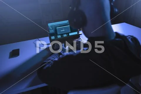 Hacker with loading bar on laptop in dark room Stock Photos