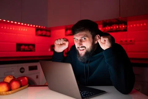 Hacker a man with a beard at a laptop Stock Photos