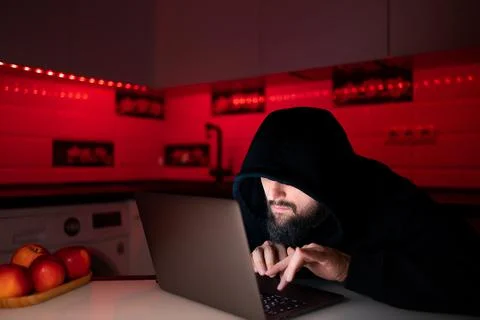 Hacker a man with a beard at a laptop Stock Photos