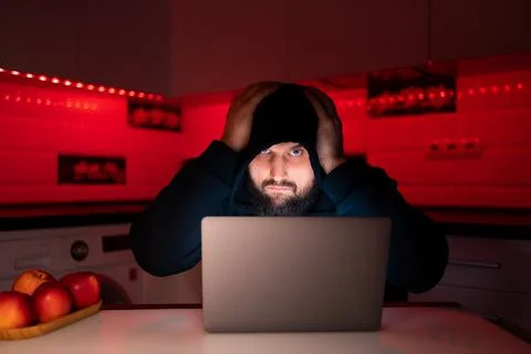 Hacker a man with a beard at a laptop Stock Photos