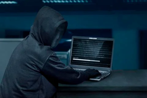 Hacker man wearing mask using laptop to upload computer virus 写真素材