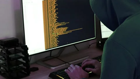 A hacker man writes the orange code for an attack. Program a virus with your  Stock Footage 143878705