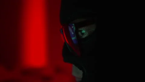 Hacker in a mask and glasses hacks into the system, a code with a running line Video stock 238027667