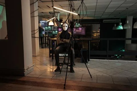 Hacker with mask threatening to expose important data on live broadcast Stock Photos