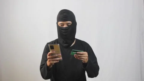 Hacker in mask using stolen credit card and phone for cyber crime Stock Footage 319367155
