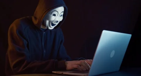Hacker with masked face uses laptop to hack data. Video stock 145027618