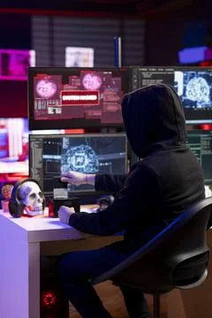 Hacker in neon apartment inserting SSD with stealth malware in PC Stock Photos