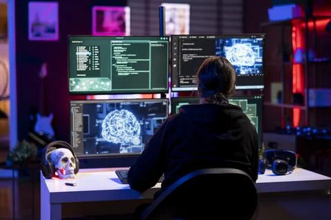 Hacker in neon lit hideout using artificial intelligence to break into systems Stock Photos