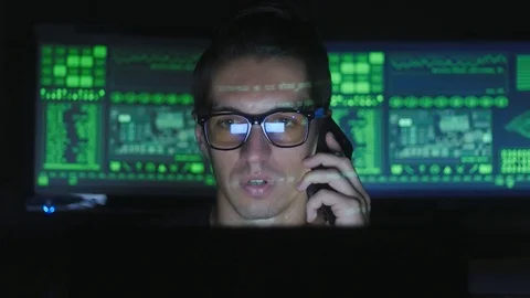 Hacker programmer in glasses is talking on the phone in cyber security center Stock-Footage 80278265