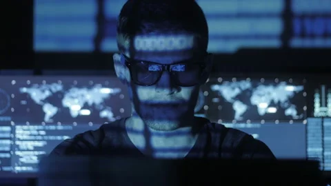 Hacker programmer in glasses is working on computer while blue binary code Stock Footage 87350452