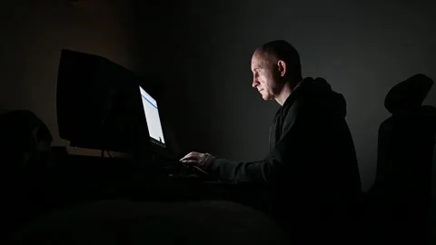 Hacker programming and typing on laptop computer at night his face illuminated Stock Footage 342230515