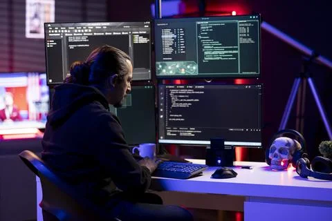 Hacker in secret hideout installing spyware secretly gathering data about user Stock Photos