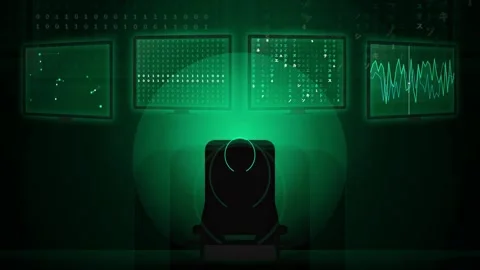 Hacker silhouette sitting in front of multiple computer screens with green Видео 343155878