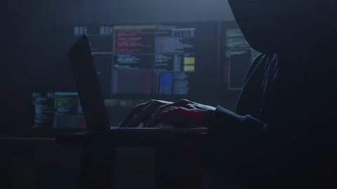 A hacker sits in a dark room, staring at code on their screen Stockbeeldmateriaal 281759392