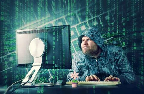 Hacker sitting at desk looking on computer screen Stock Photos