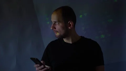 Hacker with a smartphone in hand on the background of binary codes from monitor Stock Footage 99736383