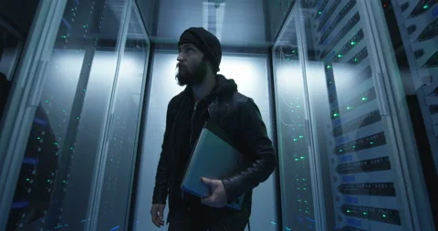 Hacker sneaking through rows of servers with laptop Stock Footage 97203977