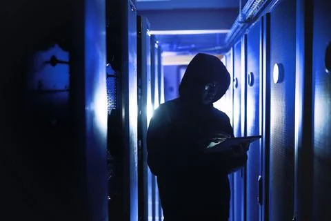 Hacker, tablet and criminal with typing in server room for cyber crime, phishing Stock Photos
