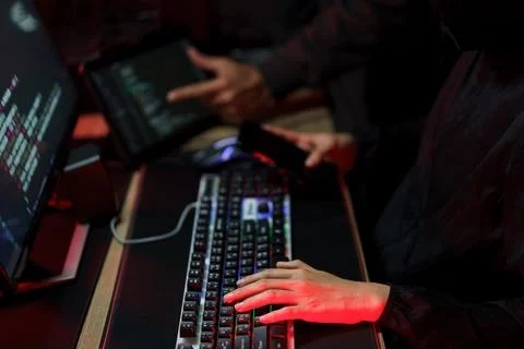 Hacker team using smartphone and typing code on keyboard to hacking program.. Photos