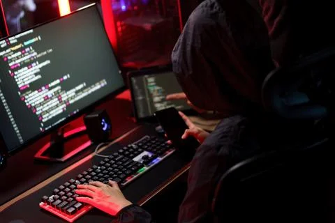 Hacker team using smartphone and typing code on keyboard to hacking program.. Foto stock