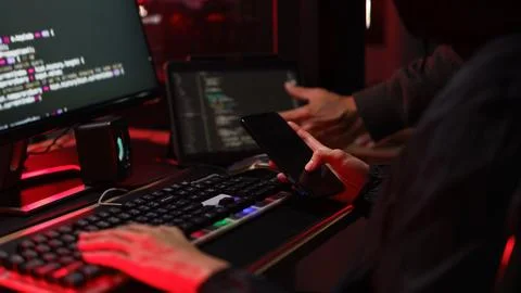 Hacker team using smartphone and typing code on keyboard to hacking program.. Foto stock