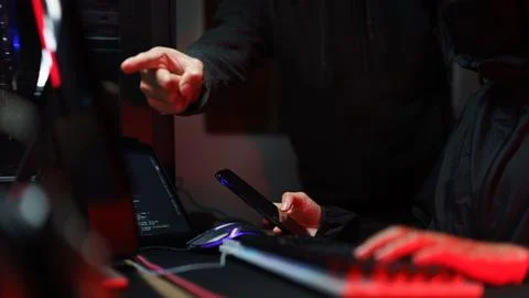 Hacker team using smartphone and typing code on keyboard to hacking program.. Photos