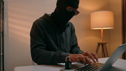 A hacker types on a laptop next to a padlock. Stock Footage 316567803