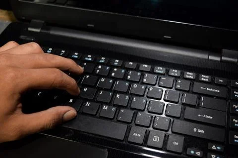 Hacker typing code on laptop keyboard with his fingers Stock Photos