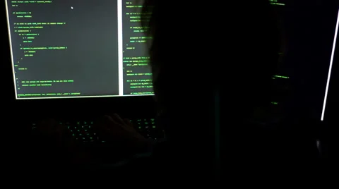 A hacker is typing code on multiple screens in darkness Stockbeeldmateriaal 33339835