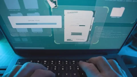 Hacker typing on computer copying and downloading secret government files from 動画素材 331404725