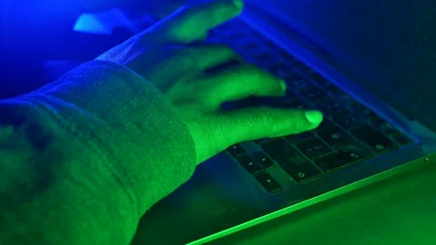 Hacker Typing on a laptop in low light with green glow, cyber crime concept Stock Footage 309443415