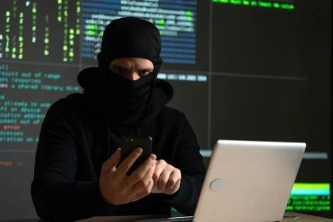 Hacker uses a mobile phone to hack the system. Stealing personal data and money Stock Photos