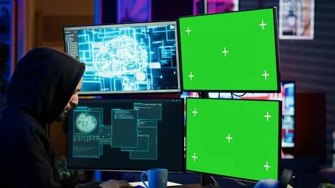 Hacker using AI and green screen computer monitors to produce malicious malware Stock Photos