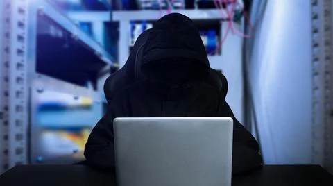 Hacker using computer with digital interface while sitting at desk of blurry Stock Photos