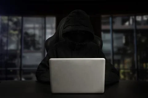 Hacker using computer with digital interface while sitting at desk of blurry Stock Photos
