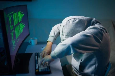 Hacker using the computer. Man in a hoodie breaks the access to steal Stock Photos