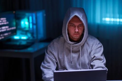 Hacker using the computer. Man in a hoodie breaks the access to steal Foto stock