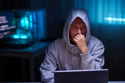 Hacker using the computer. Man in a hoodie breaks the access to steal Stock Photos