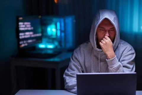 Hacker using the computer. Man in a hoodie breaks the access to steal 스톡 사진