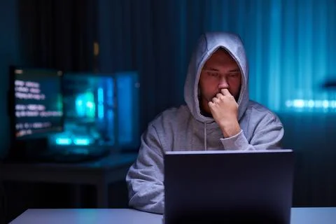 Hacker using the computer. Man in a hoodie breaks the access to steal Stock Photos