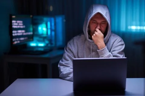Hacker using the computer. Man in a hoodie breaks the access to steal Stock Photos