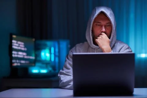 Hacker using the computer. Man in a hoodie breaks the access to steal 스톡 사진