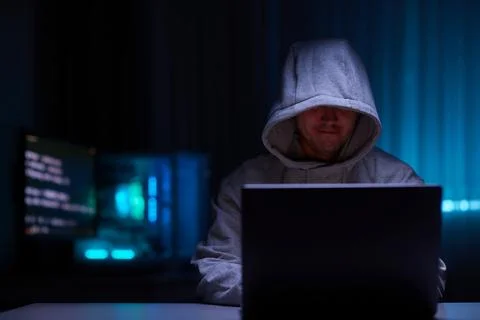 Hacker using the computer. Man in a hoodie breaks the access to steal Stock Photos