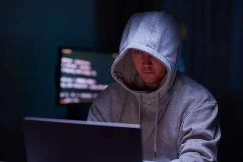 Hacker using the computer. Man in a hoodie breaks the access to steal 스톡 사진